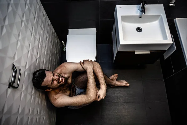 Joven desnudo gritando y llorando en el suelo en la sala de descanso. Se sienta cerca del baño y sufre. Grandes problemas. Desesperación . — Foto de Stock