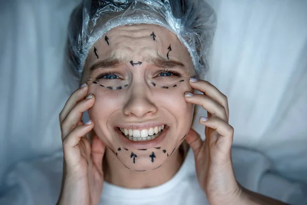 Mujer joven acostada en un sofá con gorra y llorando. Sufre de dolor. La modelo toca su cara. Está marcado. . —  Fotos de Stock