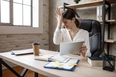 Üzgün genç işkadını odasındaki masada. O el tablet tutun. Başka bir dokunmatik alın. Meşgul.