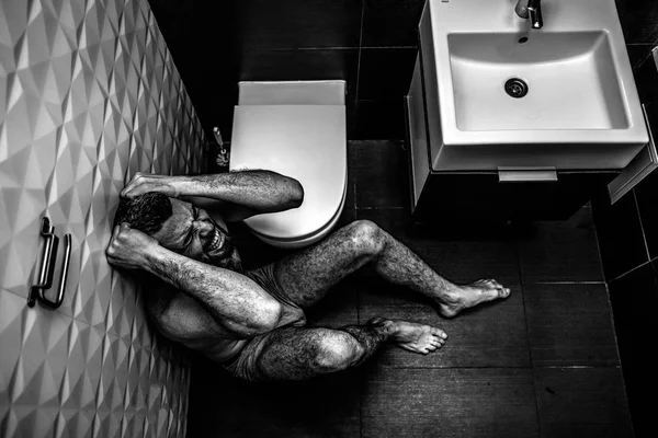 감정적인 젊은 남자 화장실 내부 바닥에 앉아서 고통. 가 금 머리와 외침과 비명에 손. 벌 거 벗은 고 외로운. 흑인과 백인 사진. — 스톡 사진