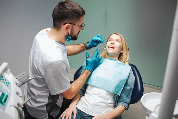 Dentiste debout client uppon et en utilisant une seringue pour mettre un analgésique. Le client s'assoit calme dans sa chaise et garde la bouche ouverte. Dentiste prudent. Patient client . — Photo