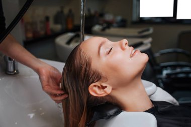 Kapalı gözlerle Kuaför saç şampuanı sonra yükselen iken gülümseyen güzel genç kadın yan görünüm. Saç spa Güzellik Salonu