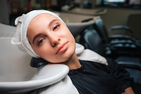Zbliżenie piękna kobieta zrelaksowany z ręcznik na głowę patrząc na kamery po umyciu włosów zawodowych. Pielęgnacja włosów w salonie piękności — Zdjęcie stockowe