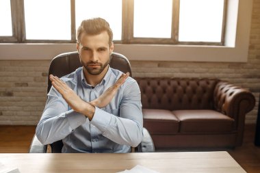 Genç yakışıklı işadamı kendi ofisinde masada otur. Yasak işareti geçti tutuşsun. Kızgın ve çok ciddi.