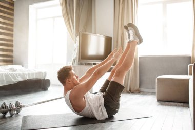 Genç kaslı adam oraya spor daire için. O yatan geri ve elleri ile ayakları ulaşmak. Genç adam germe. Yoga egzersiz.