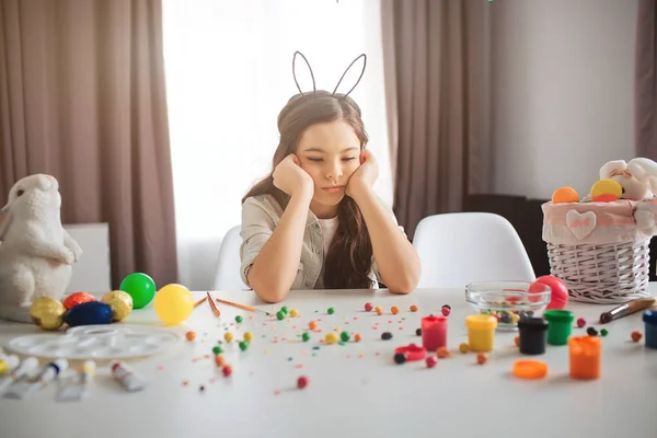 Zdenerwowana dziewczyna przygotować na Wielkanoc. Ona siedzieć przy stole pełne słodyczy i kolorowy. Dziewczyna sama w pokoju. Sad i zdenerwowany. — Zdjęcie stockowe