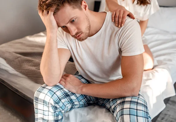 Young couple in the bed. Close-up of unhappy man is sitting on the edge of bed, problem in the bedroom — Stock Photo, Image