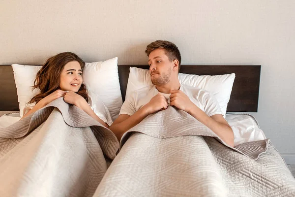 ベッドで若いカップル。セックス、内気な女、男 hidding 親密さ前に毛布の下の恐怖 — ストック写真