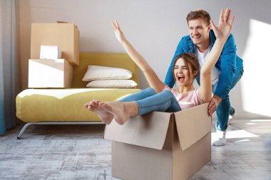 Genç aile çift satın veya kendi ilk küçük Daire Kiralık. Neşeli mutlu insanlar eğleniyor. O kutu ve çığlık içinde oturmak. Adam onu taşımak. Taşıma ve açma.