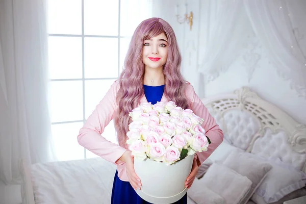 Mode-Freak. Glamour lächelnde schöne Frau mit langen lila Haaren hält weißen Kasten mit Blumen in der Hand, während sie im weißen Schlafzimmer steht. Schönheits- und Modekonzept. — Stockfoto