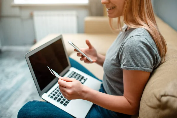 Online-Shopping zu Hause. Junger lächelnder Einkäufer mit Kreditkarte, Smartphone und Laptop ist bereit für den schwarzen Freitag — Stockfoto