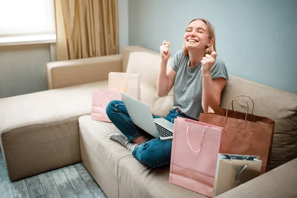 Compras en línea en casa. Joven mujer feliz con está esperando a que comience el viernes negro mientras está sentado en un sofá con bolsas de compras — Foto de Stock