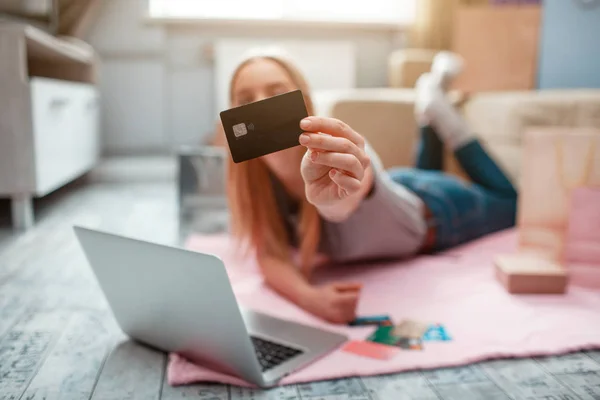 Online shopping at home. Hand is holding bank card on a background of a woman with laptop