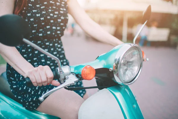 Young cheerful girl driving scooter in in city. Portrait of a young and stylish woman with a moped