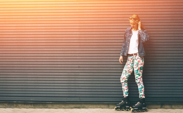 Pretty blonde girl posing with roller skates outdoors. Summer lifestyle portrait