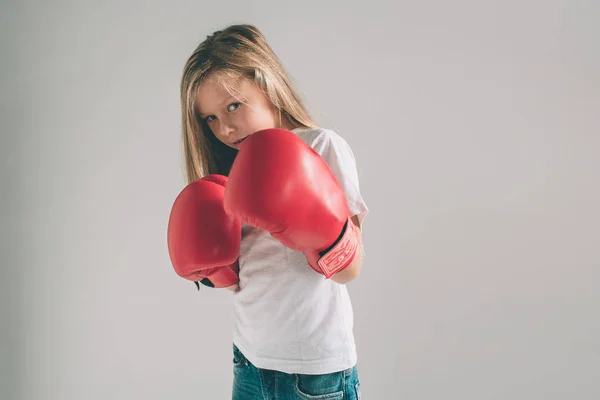 Niña cobarde divertida en guantes de boxeo rojos sobre fondo blanco . —  Fotos de Stock