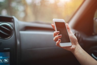 Ön yolcu koltukları arabada otururken gülümseyen eautiful kadın. Kız bir akıllı telefon kullanıyor. El portre