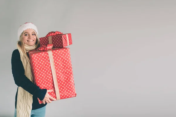 Mujer con sombrero de Navidad y gafas con regalos sobre fondo blanco. Chica de camisa blanca, tiro al estudio — Foto de Stock