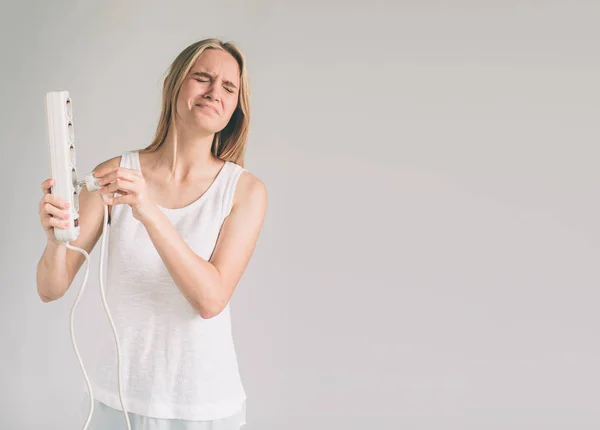 S úsměvem šťastná žena pomocí plug pull out zásuvky ukazující šetří elektrický koncept izolovaných na zeď na pozadí s životní styl oblečení — Stock fotografie