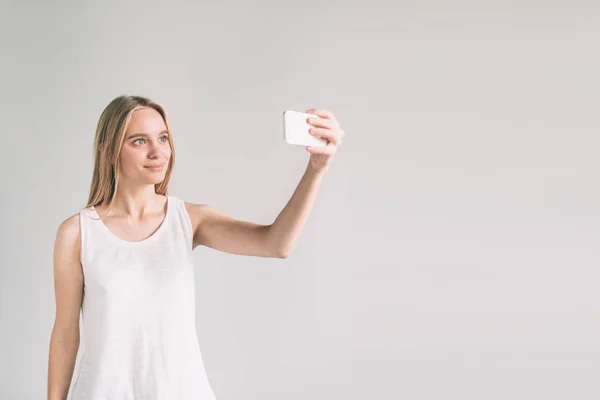Flicka i vit skjorta, studio skott. Kvinnor tar en selfie. — Stockfoto