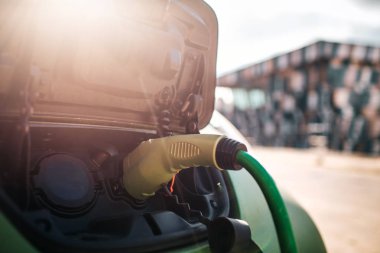 Elektrikli araç şarj istasyonu. Güç kablosu kaynağına takılı bir elektrikli aracın şarj edilmesi. Çevre dostu araba