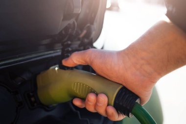 Elektrikli araç şarj istasyonu. Güç kablosu kaynağı takılı bir elektrikli araba şarj el yakın çekim. Çevre dostu araba