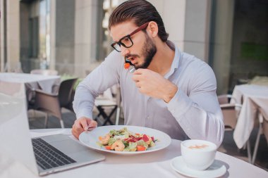 Meşgul bir adam cevap telefon görüşmesi sırasında öğle yemeği. Görüşmeler ve plaka salata ile aynı anda tutar. Kahve de vardır.