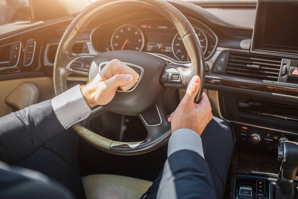 Изображение руки человека, использующего предупреждение на руле. Он водит машину. На улице солнечно.
.