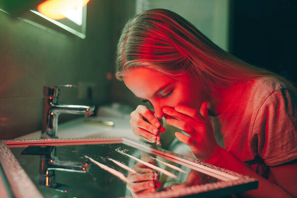 Drugs destroy your life. Young drug addict prepares to take cocaine with rolled banknote from glass surface in night clubs toilet. Say no to drugs. Stop drug abuse