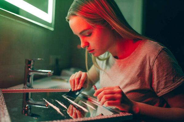 Drugs kill you. Young drug addict making cocaine line with black credit card on glass surface in night clubs toilet. Say no to drugs. Stop drug abuse