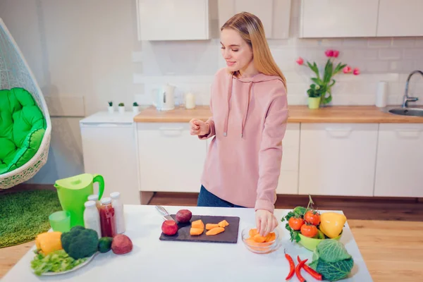 Vegan beautiful blonde woman cooking raw vegetables in the kitchen. Vegetarian food. Healthy eating. Vegan diet — Stock Photo, Image