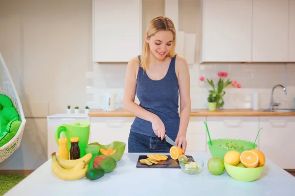 Jeune femme blonde souriante cuisinant des fruits frais dans la cuisine. Une nourriture saine. Repas végétarien. Désintoxication alimentaire — Photo