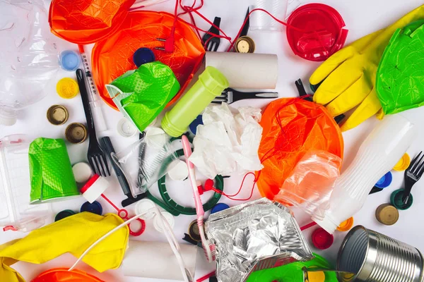 Plastic pollution concept. Be plastic free. Broken single-use colorful plates, forks, cups, bottle, straw, toothbrush, lids, foil and other plastic trash on white background. New rules to reduce