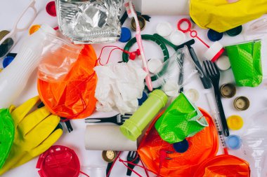 Plastik kirlilik kavramı. Plastik ücretsiz olun. Kırık tek kullanımlık renkli plakalar, çatal, bardak, şişe, saman, diş fırçası, kapaklar, folyo ve beyaz arka planda diğer plastik çöp. Azaltmak için yeni kurallar