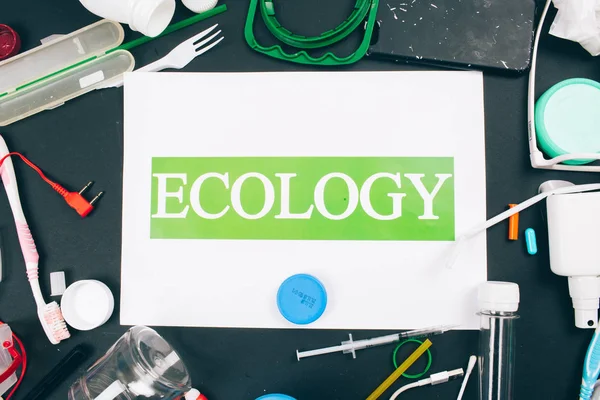 Plastic pollution concept. Save marine ecology. Paper with word Ecology in the center of colorful single-use plastic waste on dark background. An environment problem, EU directive. Top view — Stock Photo, Image