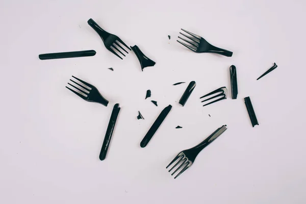 Plastic pollution concept. Plastic free. Broken single-use black forks on dark background, top view. New rules to reduce plastic waste, EU directive. We can no longer pollute our planet