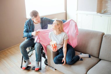 Engelli ve kapsayıcı kişi kız arkadaşı dikkat çekmek. Tekerlekli sandalyeye oturmuş omzuna battaniye örtmüş. Geriye bakıp gülümsüyor. Özel ihtiyaçları olan kişi.