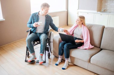 Özürlü genç bir öğrenci kız arkadaşıyla ilgileniyor. Özel ihtiyaçları olan adam. Kanepeye oturup dizüstü bilgisayar tutuyor. Adam ona bir fincan kahve verdi. Öğrenciler birlikte..