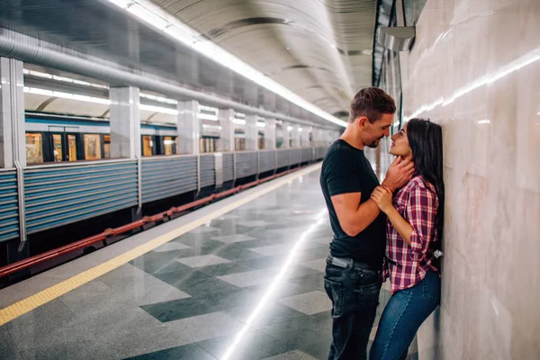 若い男と女は地下を使う地下鉄でカップル。陽気な情熱的な人々の壁にもたれる。キスの時間だ男が首を握ってるラブストーリー。近代都市景観. — ストック写真