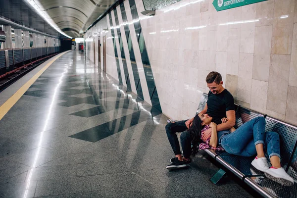Mladý muž a žena používají podzemí. Pár v metru. Mladá žena ležela na klucích a spala. Podíval se na ni a objal se. Láska na první pohled. Valentýn. Milostný příběh. — Stock fotografie