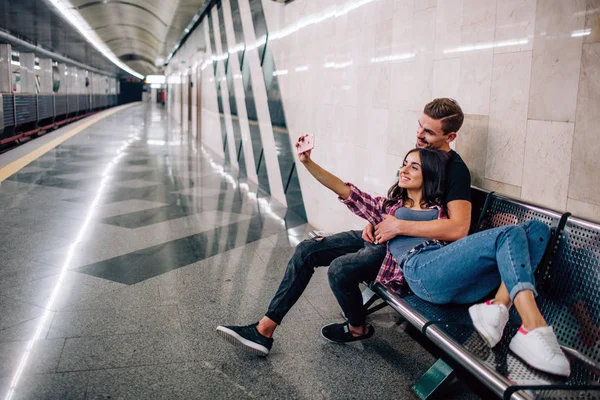 年轻人在地下活动。 一对夫妇在地铁里。 年轻女子在空荡荡的地铁站为自己和男友自私自利。 笑着摆姿势 爱情故事. — 图库照片