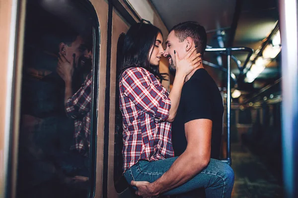 Jovem e mulher usam o subterrâneo. Um casal no metro. Beijo apaixonado. Jovem, segura a mulher com as mãos. Perto um do outro. Transporte subterrâneo . — Fotografia de Stock
