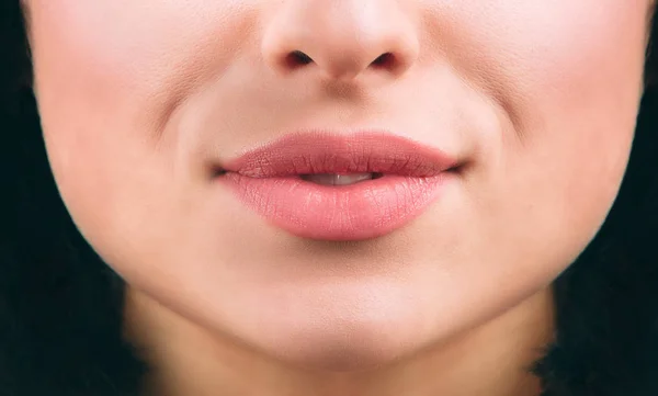 Close up of nice young womans lips smiling a bit. Short black hair. Healthy skin. Cut view.