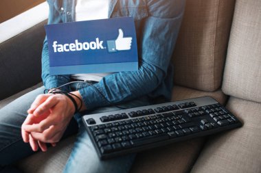 Kiev, Ukrayna - 26 Nisan 2019: Facebook logosu. Illüstrasyon. Facebook simgesi. Genç adamın sosyal medya bağımlılığı var. Dizüstü bilgisayardan bağımlılık. Resimdeki klavye. Eller sarılır.