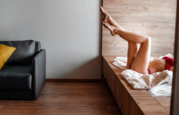Seductora joven mujer morena desnuda en la cama por la mañana. Vista de corte de bien construido delgado caliente sexy modelo acostado y posando. Hermosas piernas. Solo en la habitación . —  Fotos de Stock