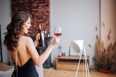 Genç kadının alkol le ilgili sorunları var. Güzel iyi inşa edilmiş ve ince model siyah takım elbise şarap ile şişe ve cam tutun. Geri dönüp çığlık atıyor. Oturma odasında tek başına.