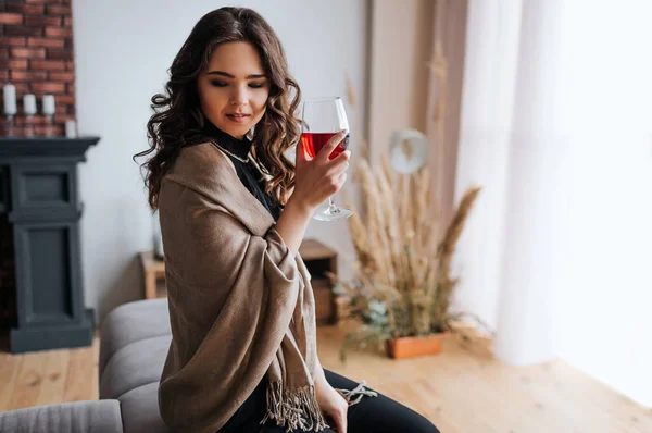 Ung affärskvinna arbetar hemma. Håll glas rött vin i handen. Vacker modell i aftonklänning stå vid fönstret. Ensam i rummet. — Stockfoto