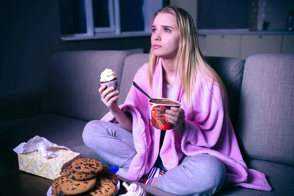 Young woman watching movie at night. Blonde model sitting with hands crossed. Eating pancake and ice cream. Streaming show or tv series. — Stock Photo, Image