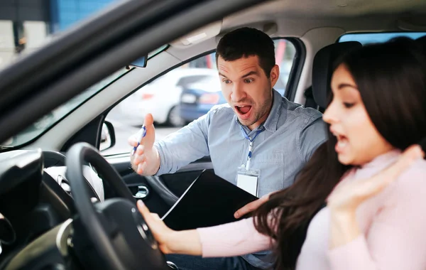 Homme instructeur auto prend examen chez la jeune femme. Crier sur la brune et pointer avec la main. Elle regarde vers le bas et siège. Stress et situation inconfortable . — Photo