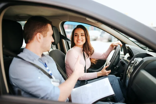 Hombre auto instructor toma examen en mujer joven. Cuestión práctica. Alegre feliz y positivo estudiante mira al profesor y sonríe . — Foto de Stock